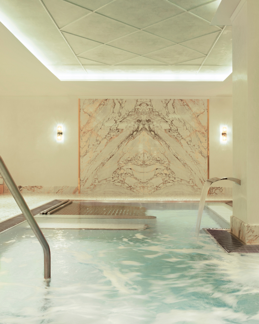 Indoor pool area with marble walls and ceiling lights
